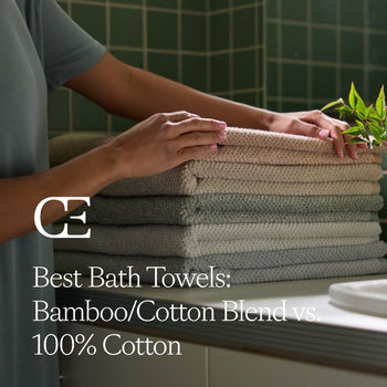 a person rests a stack of bath towels on a bathroom countertop