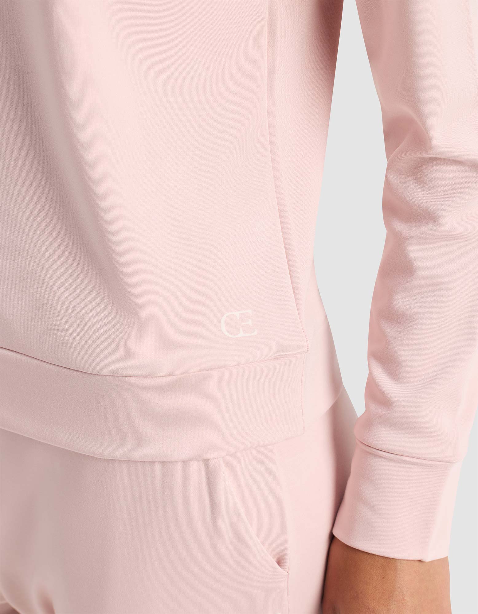 Close-up of light pink pants with a drawstring tie at the waist. The drawstring has "COZY EARTH" printed on it in white letters.