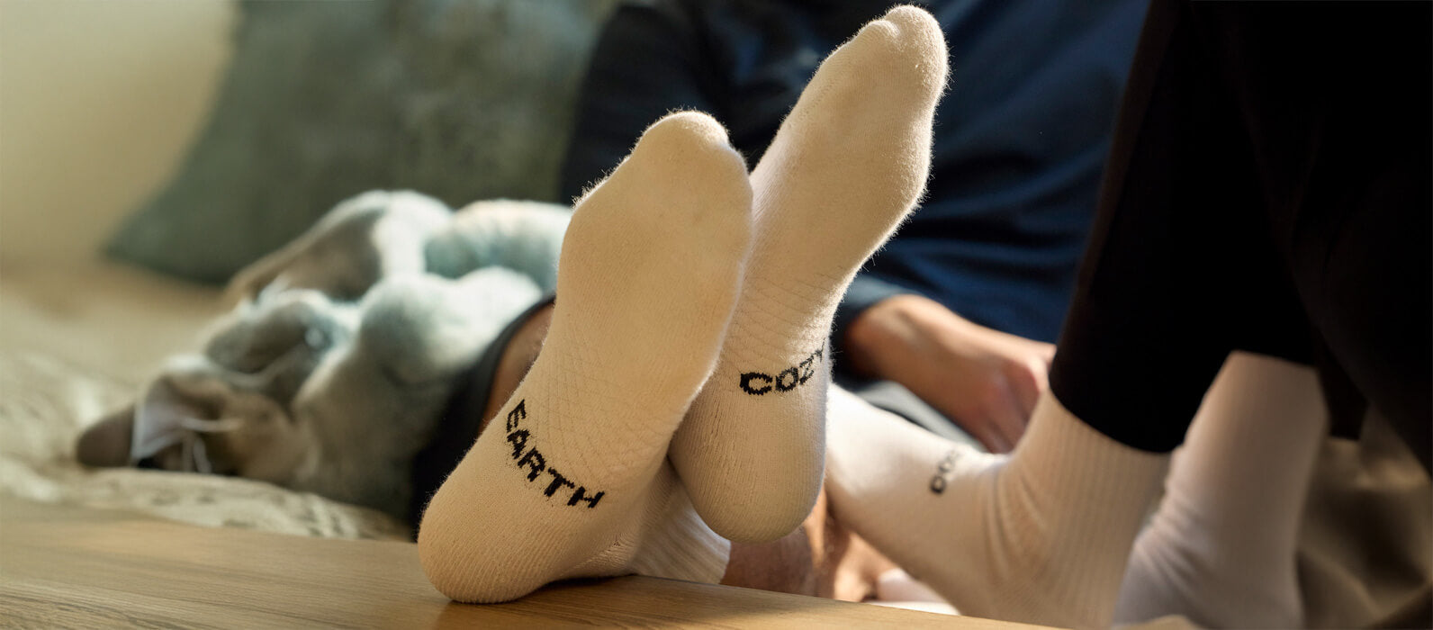 A man's feet pictured resting on a table wearing Cozy Earth socks