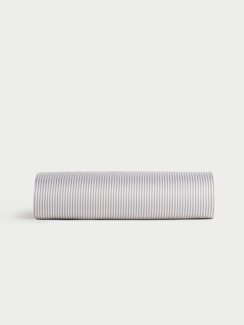 A Bamboo Duvet Cover by Cozy Earth is elegantly displayed rolled up on a plain, light-colored background. The cover features narrow, vertical black stripes on a white surface, offering a simple and clean design.