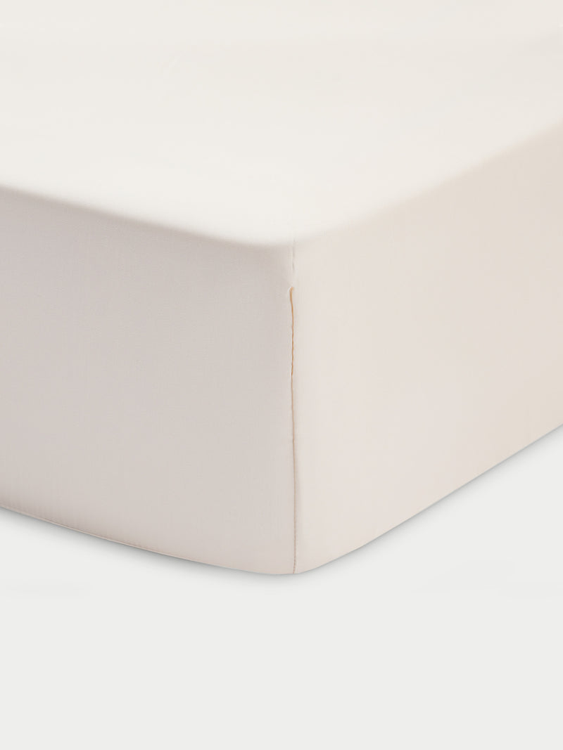 Corner of creme crib sheet with white baackground