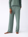 A person barefoot stands out in a relaxed, sage green loungewear set from Cozy Earth. This ensemble features an ultra-soft long-sleeve top paired with the Women's Ultra-Soft Bamboo Wide Leg Pull On Pant TALL. The plain white background highlights the outfit's soothing color and inviting comfort. |Color:Oakmoss