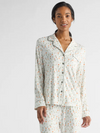 A person is wearing a matching pajama set with a pattern of small, colorful abstract shapes on a light background. They are standing and smiling with hands by their sides, against a plain, neutral backdrop.|Color:Sienna Tulips