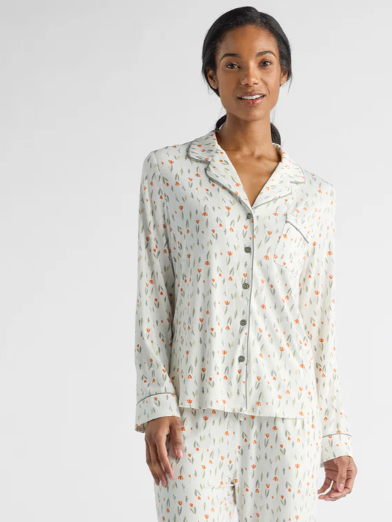 A person is wearing a matching pajama set with a pattern of small, colorful abstract shapes on a light background. They are standing and smiling with hands by their sides, against a plain, neutral backdrop.|Color:Sienna Tulips