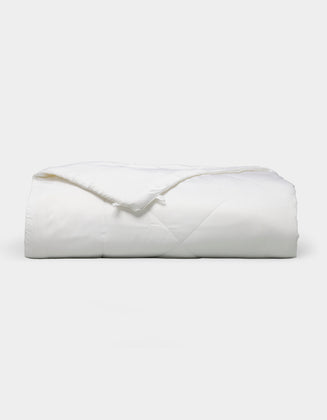 The Bamboo Viscose All Season Comforter by Cozy Earth, featuring a neatly folded white design with a subtle sheen, is displayed against a plain light background.|Filling:Standard 