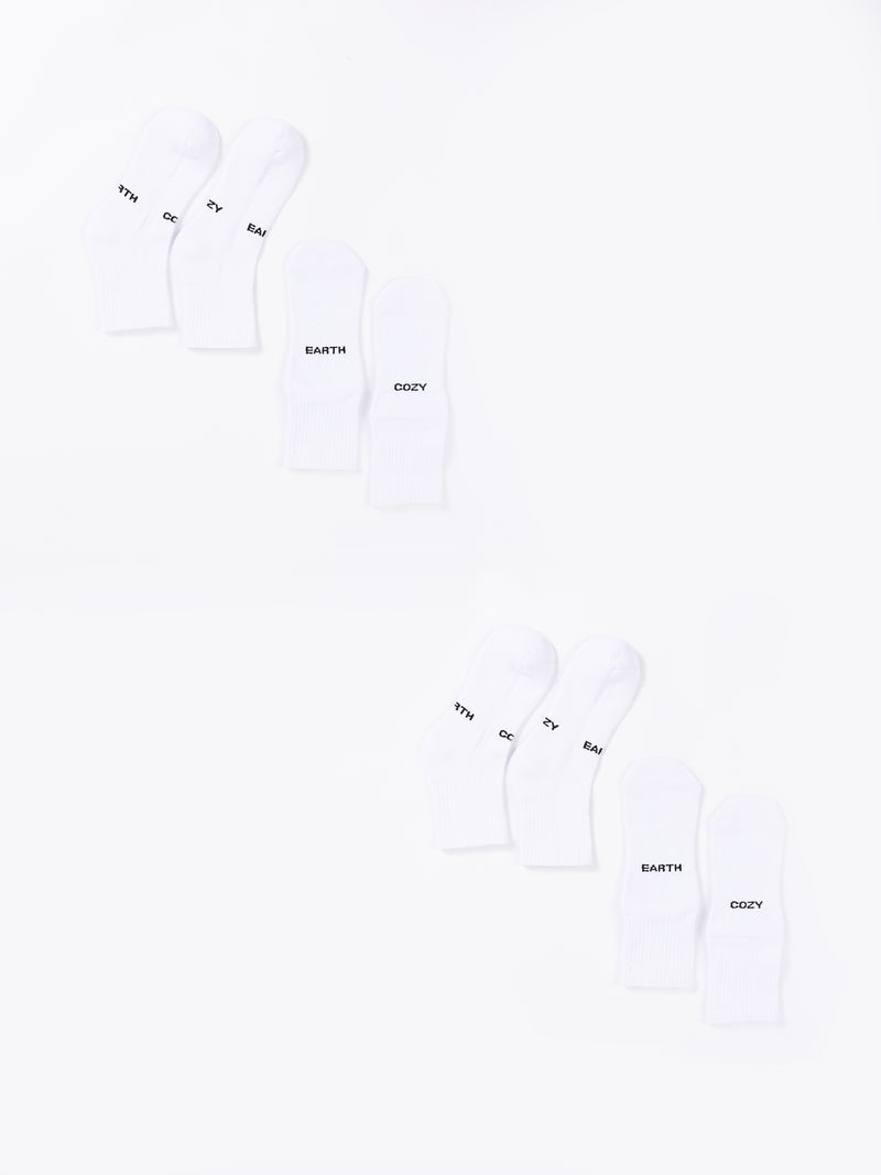The Essential Quarter Sock 4-Pack from Cozy Earth includes eight white socks arranged in two rows, with each row containing four pairs. The socks feature various words printed on them, such as "EARTH," "COZY," and "THY." The plain white background provides a clean and minimalist appearance.