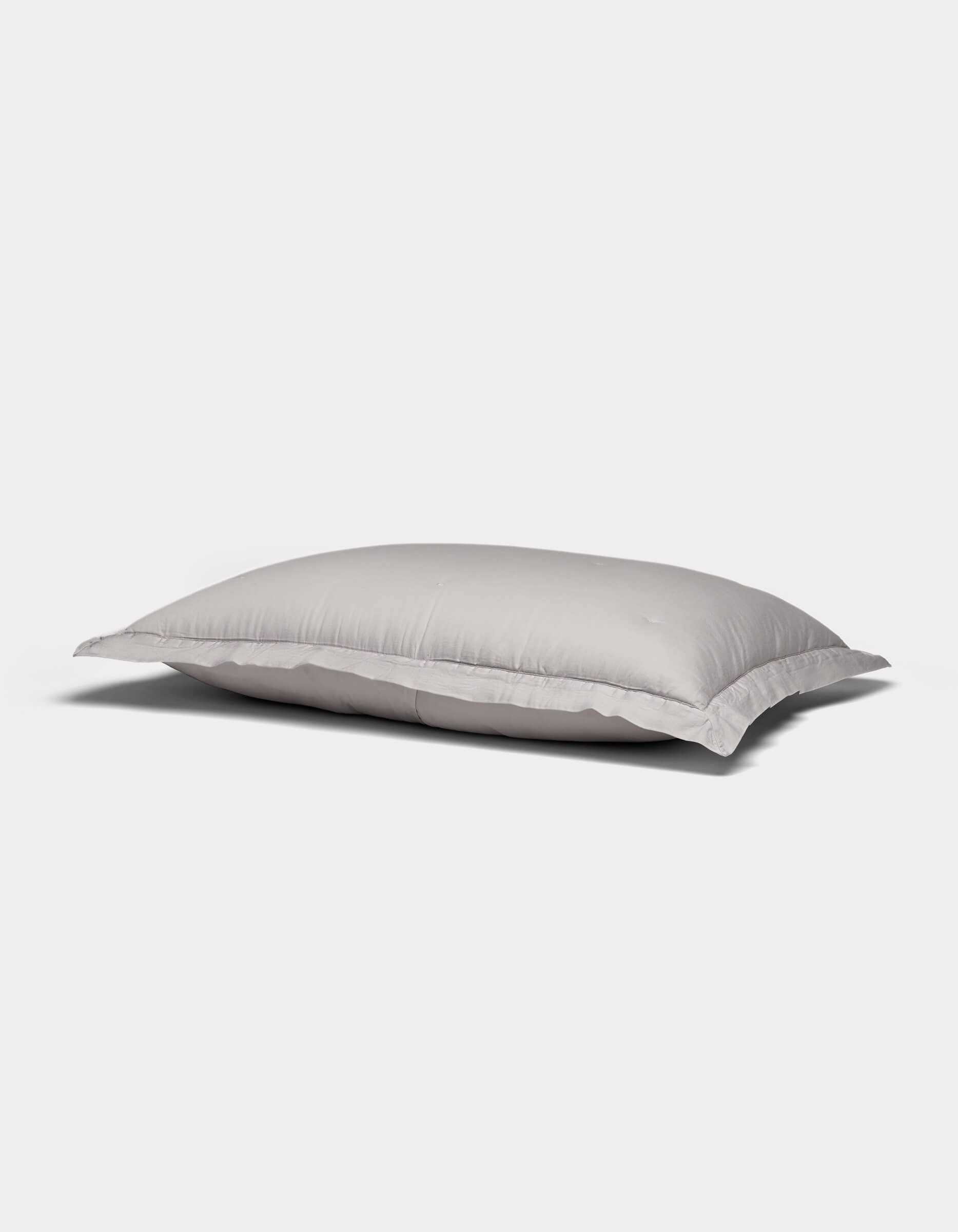 A Soft-Wash Cotton Quilted Sham by Cozy Earth, white and rectangular with a smooth surface, rests on a plain light gray background.