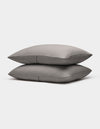 Two neatly stacked Bamboo Coverlet Shams by Cozy Earth in gray with stripes, displayed on a plain white background.|Color:Charcoal