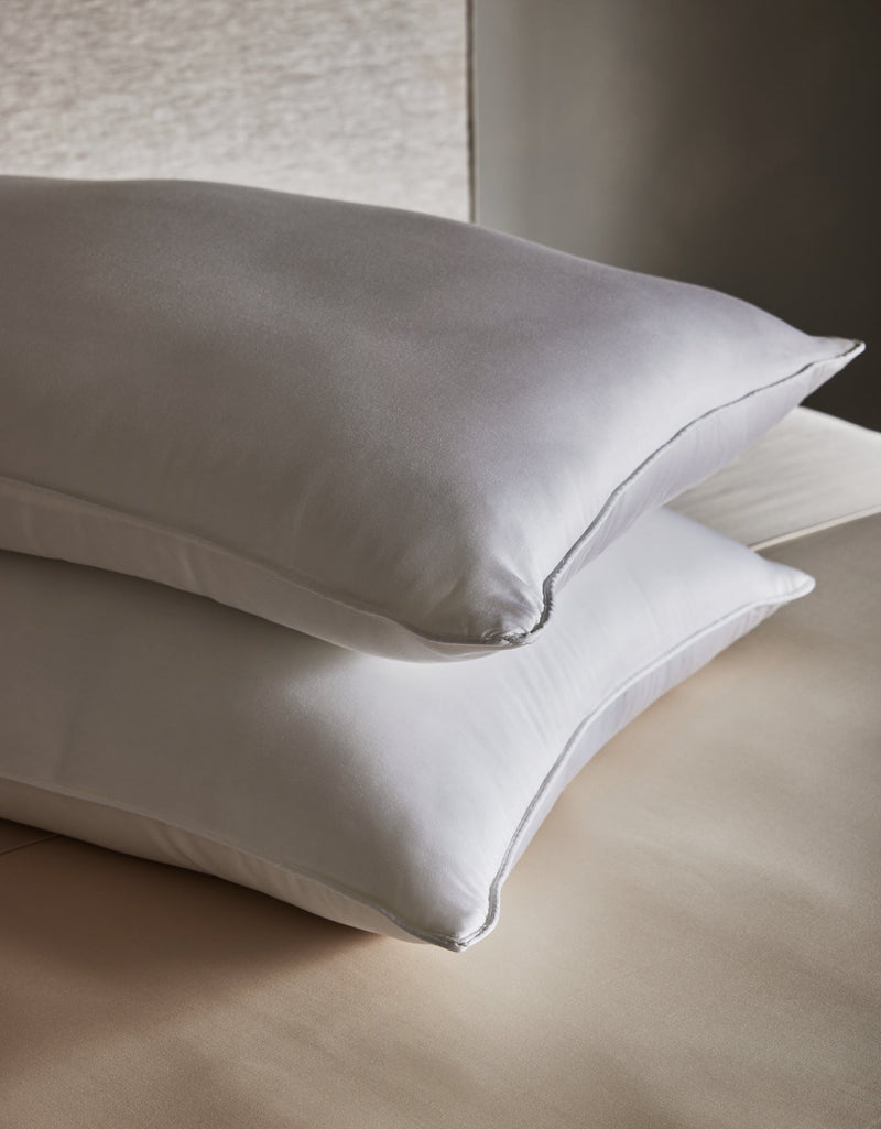 Two Cozy Earth Bamboo Down Alternative Pillows are neatly stacked on a beige bed with smooth, clean sheets, set against a neutral background.Standard King