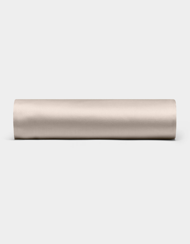 A Cozy Earth Bamboo Fitted Sheet in plain, light beige is shown lying horizontally on a white background, viewed from the side.