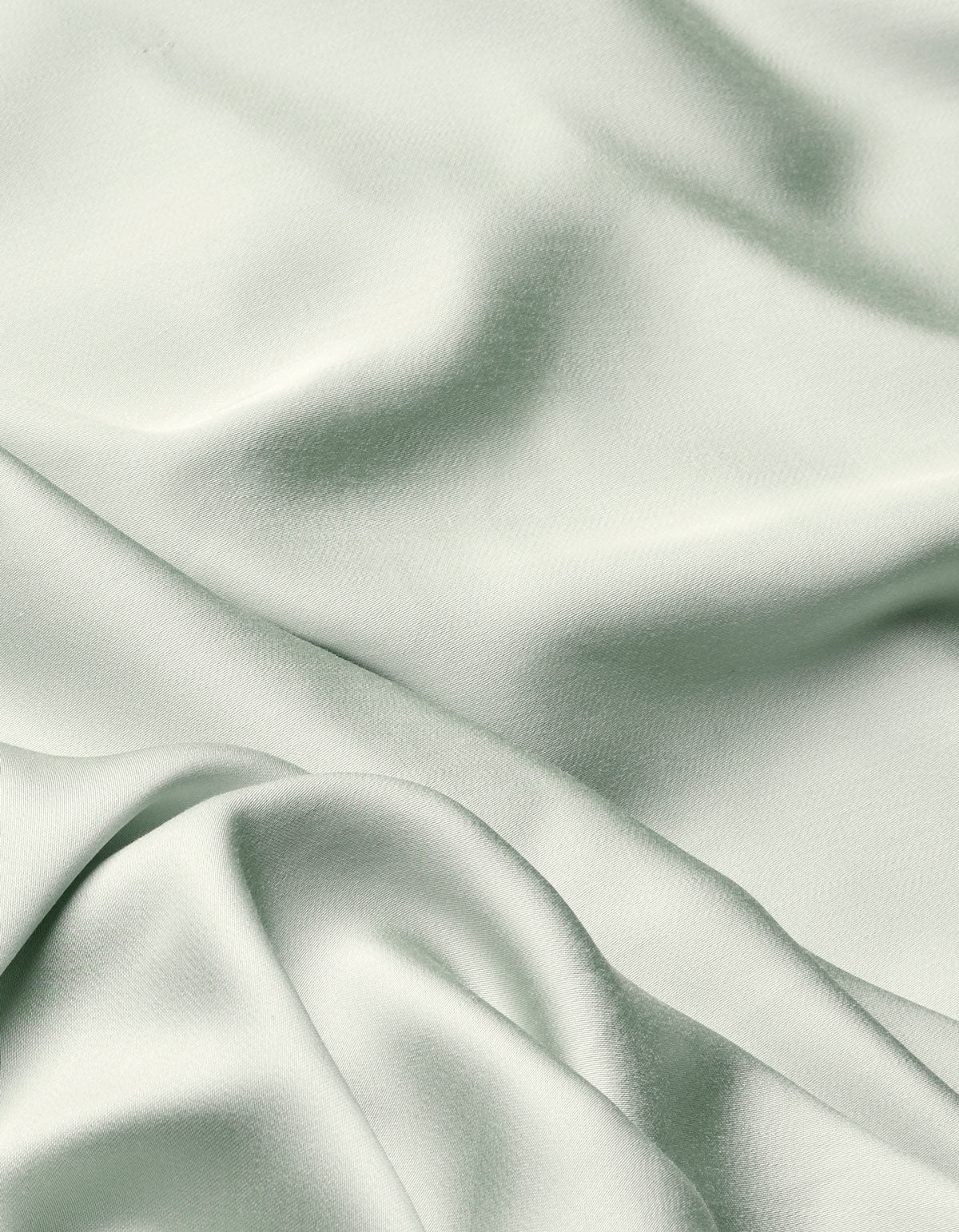 The Cozy Earth Bamboo Flat Sheet features a soft, light sage green fabric with a smooth texture and gentle folds that create subtle shadows and highlights across its surface.