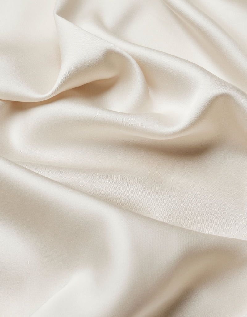 Close-up of Cozy Earth Bamboo Sheet Set in smooth, ivory satin with soft folds and gentle waves, showcasing its silky texture and subtle sheen.