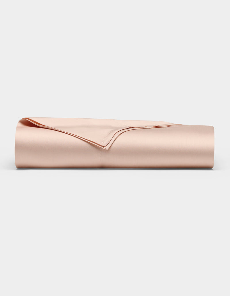 The Bamboo Flat Sheet by Cozy Earth, shown neatly folded in a light beige satin finish, is displayed against a plain white background.