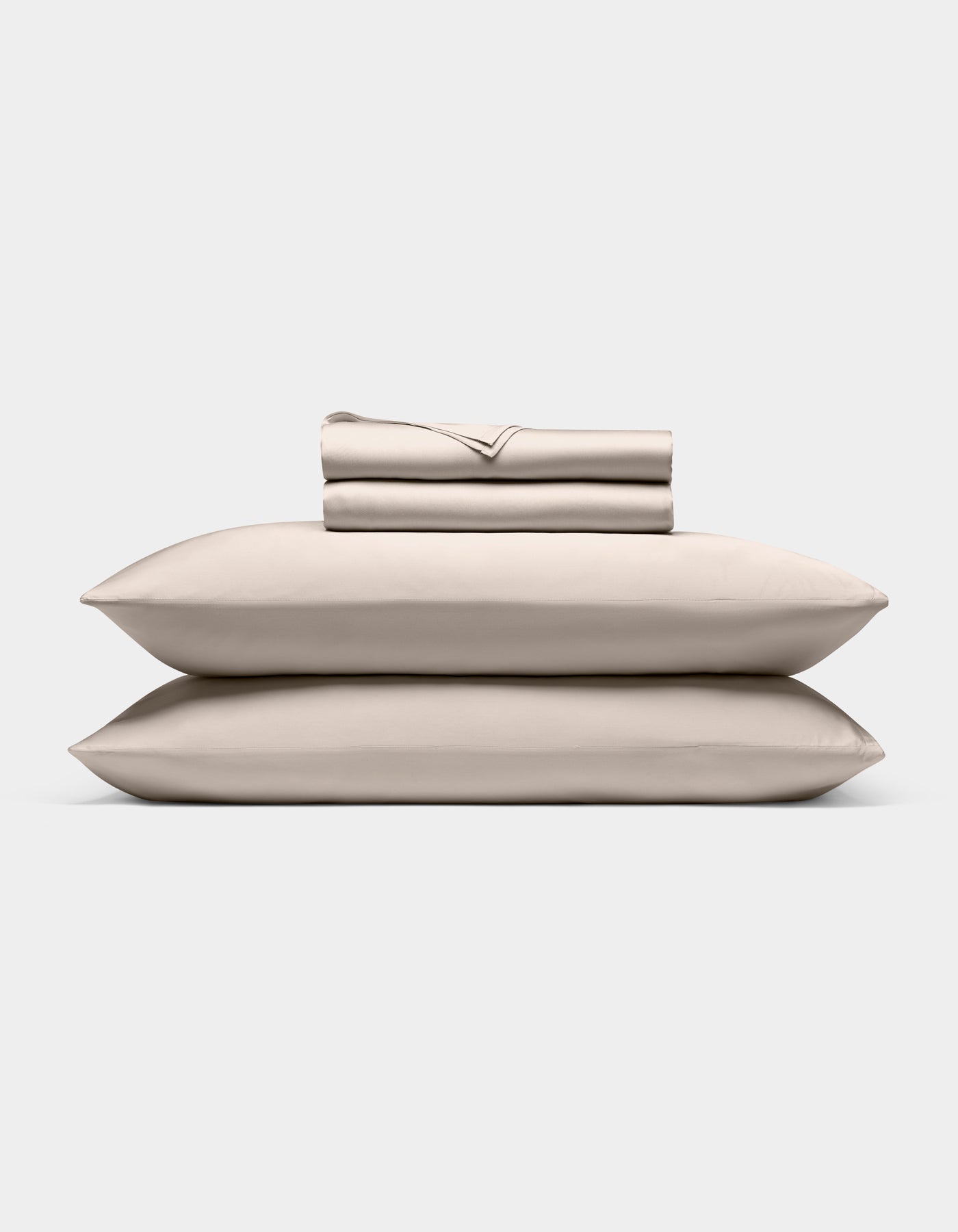A neatly stacked Cozy Earth Bamboo Sheet Set, featuring two pillows, a folded fitted sheet, flat sheet, and pillowcases, displayed against a plain white background.