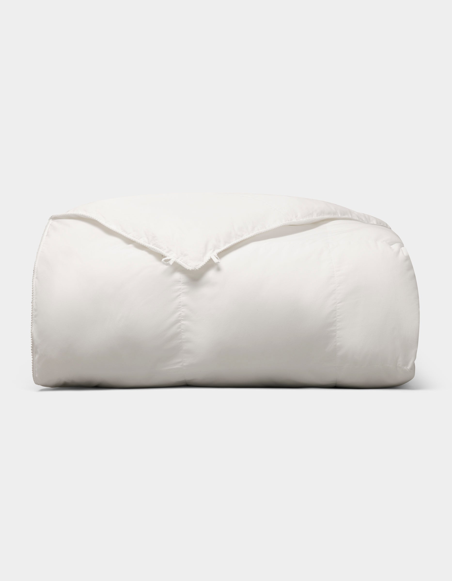 The Cozy Earth Down Alternative Comforter is neatly folded and fluffy, displayed against a plain light gray background. |Filling:Lightweight