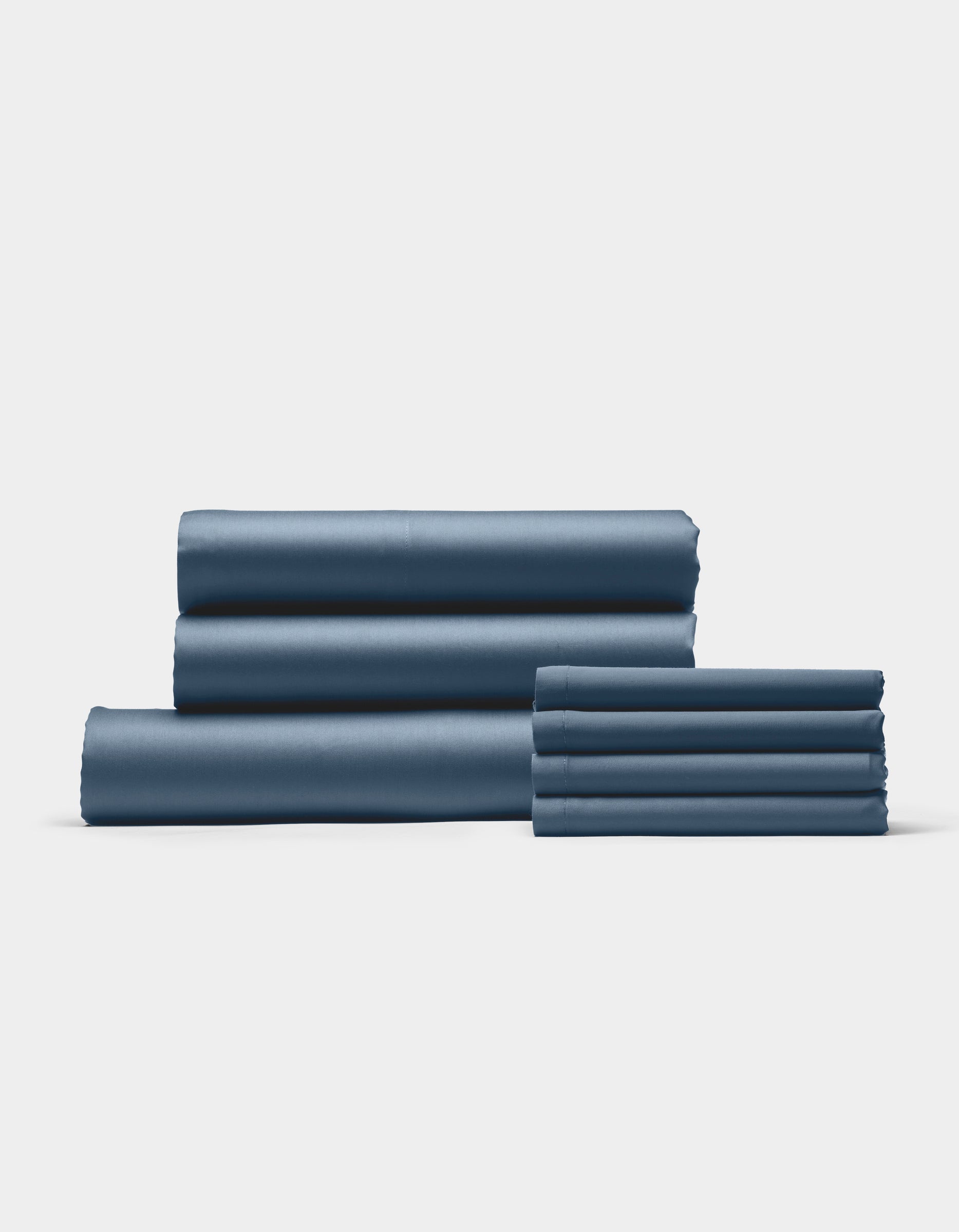 The Cozy Earth Bamboo Bedding Core Bundle features neatly folded blue bed sheets and pillowcases arranged in two stacks on a plain white background.|Color:Pacific Blue