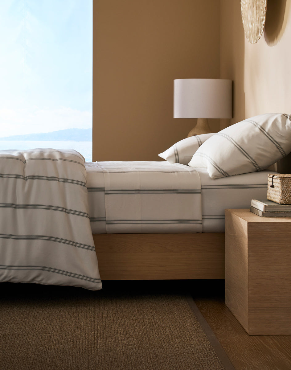 Bedroom with Cozy Earth Baja Stripe Bamboo bedding and a lamp on a nightstand.|Color:Baja Stripe in Laurel