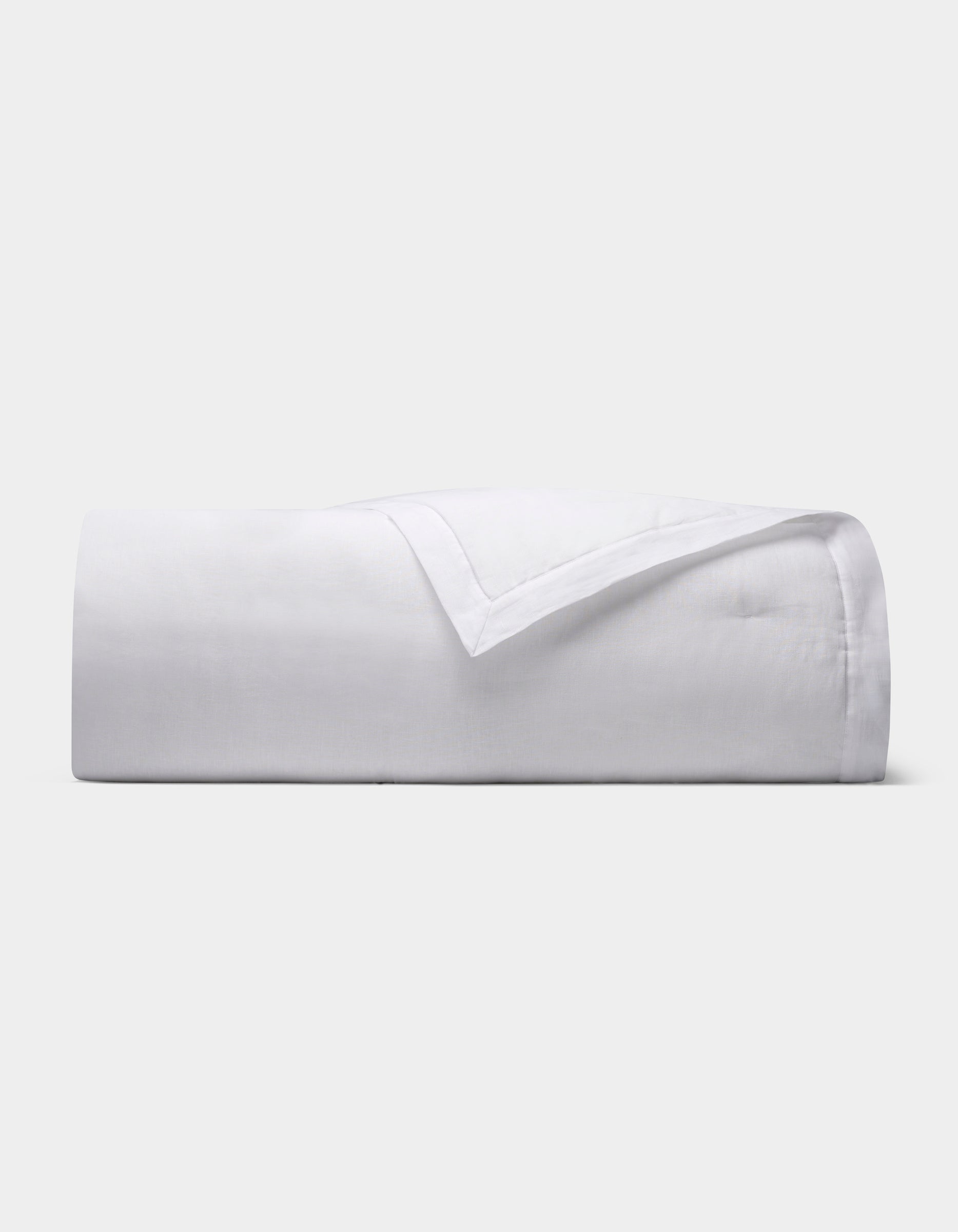 The Cozy Earth Linen Quilt, featuring a smooth texture, is neatly folded and displayed against a plain light gray background.