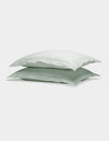 Two Cozy Earth Linen Shams in light green are neatly stacked atop each other against a plain white background.|Color:Mist