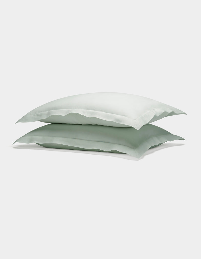 Two Cozy Earth Linen Shams in light green are neatly stacked atop each other against a plain white background.