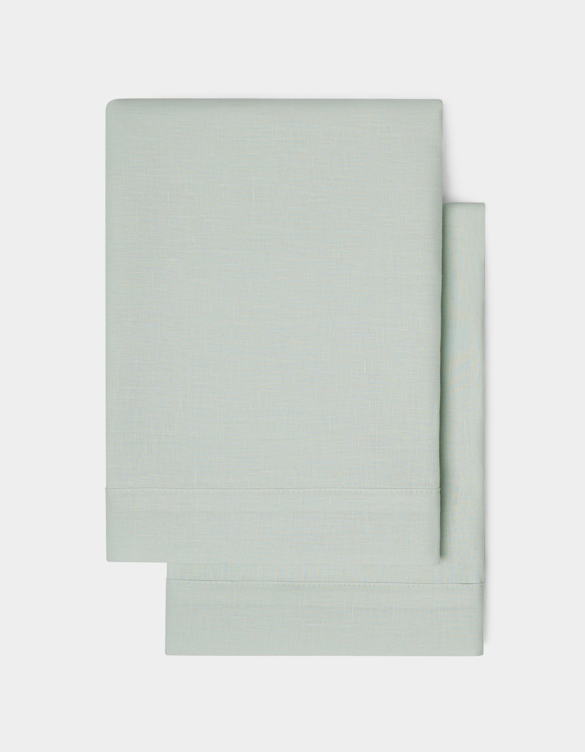 Two neatly folded Linen Shams by Cozy Earth in light gray are stacked on a plain white background, highlighting their simple and clean design.