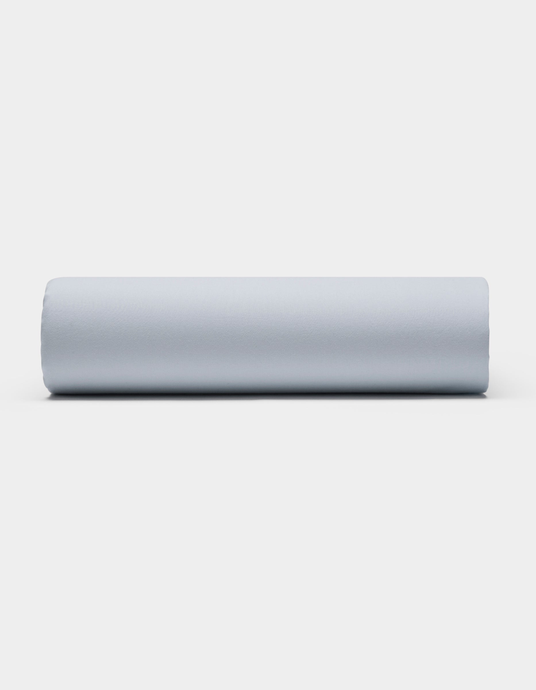 A Soft-Wash Cotton Sheet Set by Cozy Earth is displayed on a plain white background, featuring smooth, light gray fabric arranged neatly to showcase its soft texture.