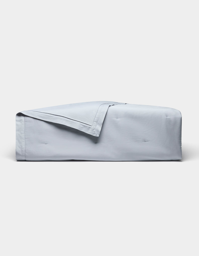 The Cozy Earth Soft-Wash Cotton Quilt, in light blue with a matching folded-back corner, is displayed on a plain white background.
