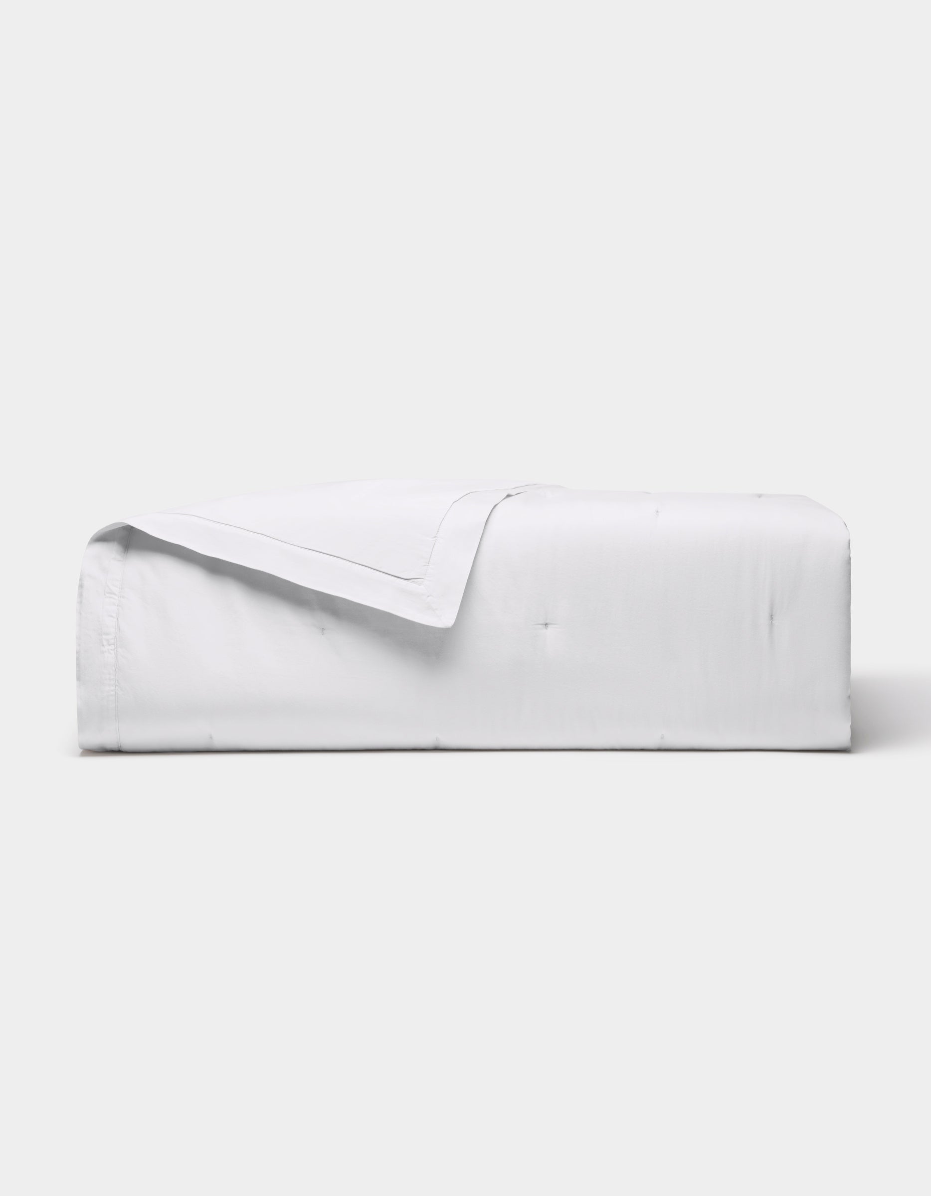 The Cozy Earth Soft-Wash Cotton Quilt is neatly folded with one corner turned down, showcased against a plain light gray background.