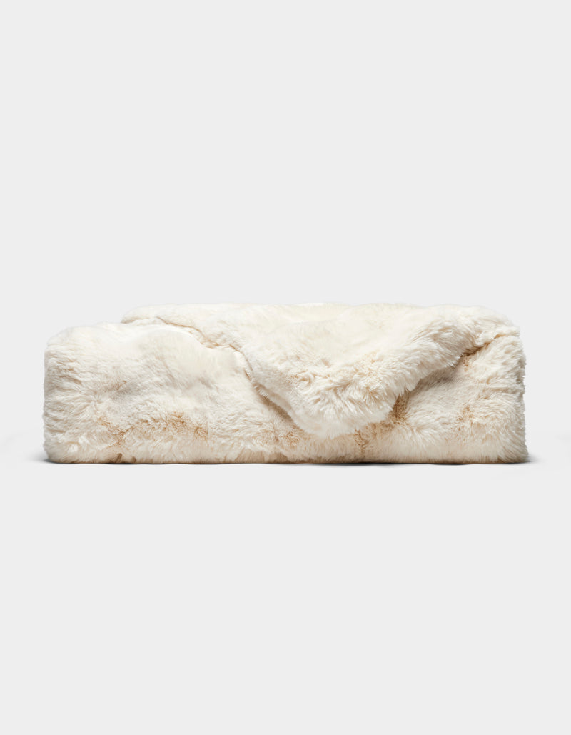 The Double Bubble Cuddle Blanket by Cozy Earth, featuring soft, cream-colored faux fur, is neatly folded on a plain light gray background.