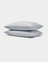 Two light gray Bamboo Jersey Pillowcases by Cozy Earth stacked neatly on each other against a plain white background.|Color:Shore