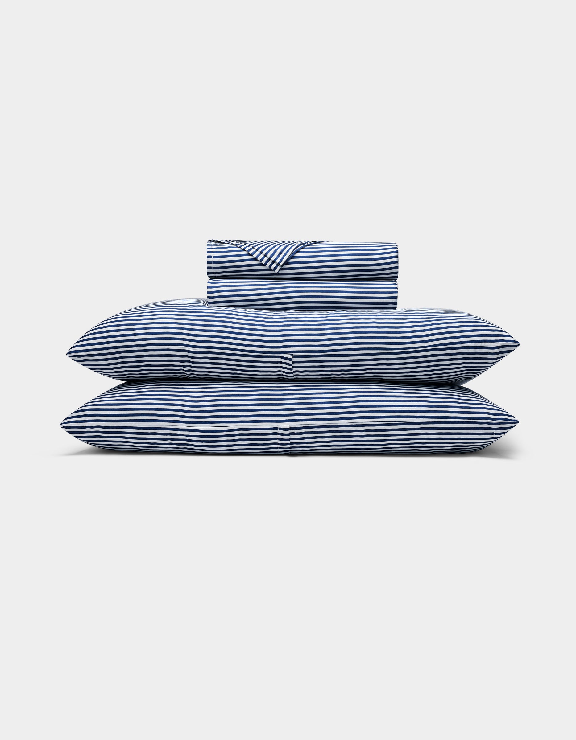 A neatly folded Bamboo Sheet Set by Cozy Earth, featuring blue and white stripes, with two pillows, a duvet, and a folded sheet stacked against a plain white background.
