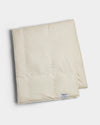 The Cozy Earth Down Alternative Throw is a folded, cream-colored quilt with a small rectangular label near the edge, displayed on a white background.|Color:Coconut