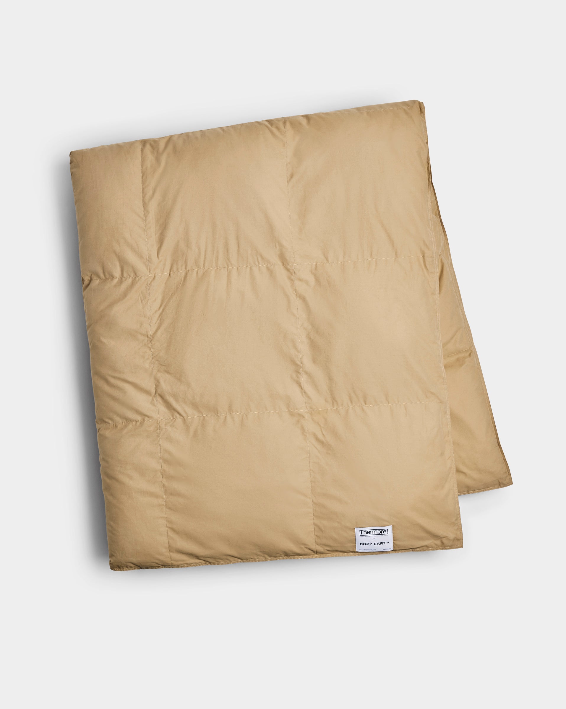The Cozy Earth Down Alternative Throw is a neatly folded, light brown quilted blanket featuring a small white tag in one corner, displayed on a plain white background.|Color:Sandalwood