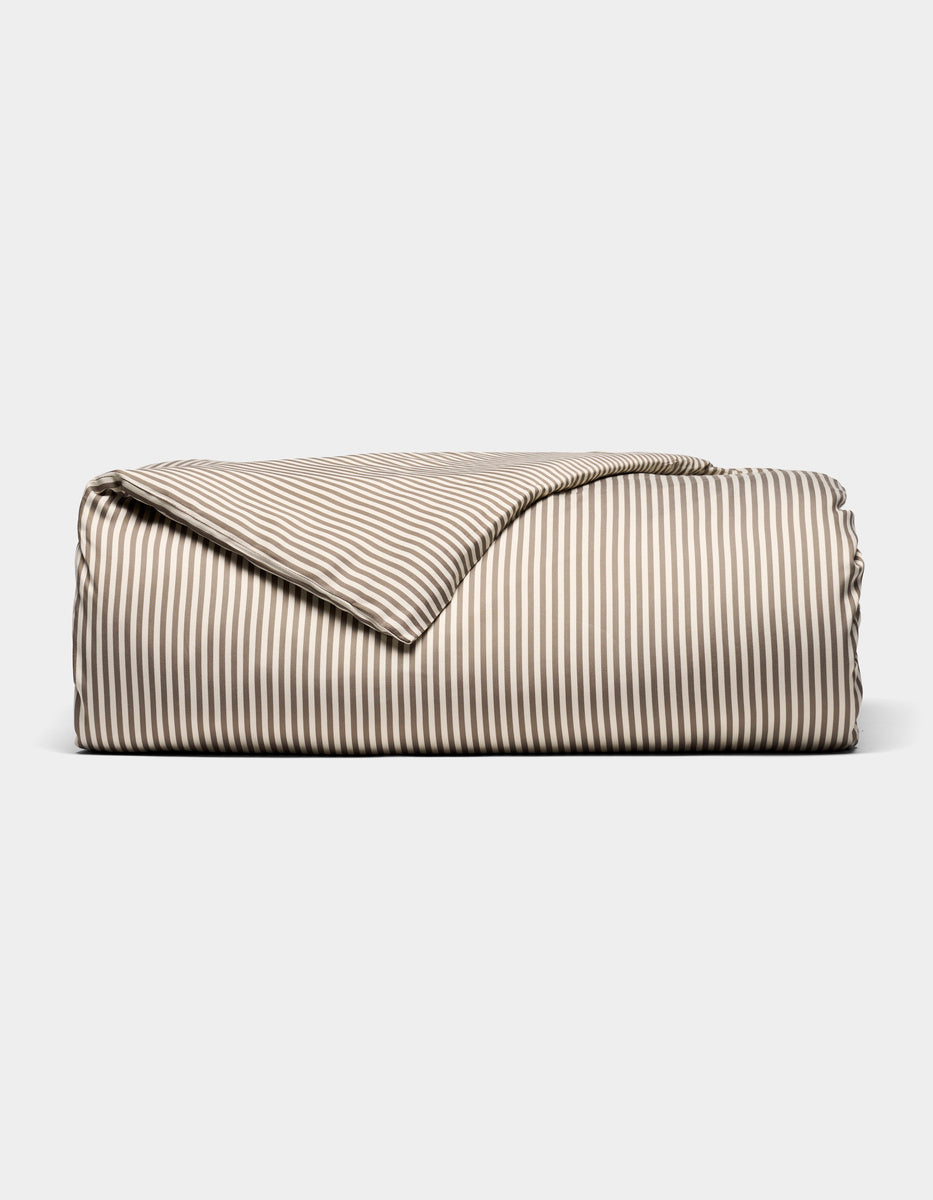 The Bamboo Duvet Cover by Cozy Earth, featuring beige and white stripes, is neatly folded and displayed against a plain white background.