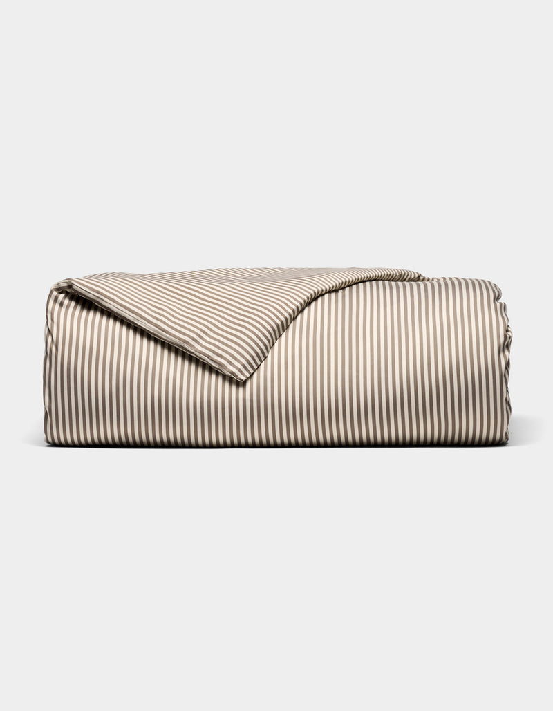 The Bamboo Duvet Cover by Cozy Earth, featuring beige and white stripes, is neatly folded and displayed against a plain white background.