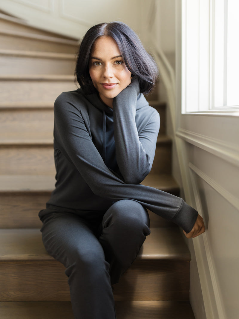 Charcoal Bamboo Jogger Set modeled by a woman. The photo was taken in a high contrast setting, showing off the colors and lines of the pajamas.