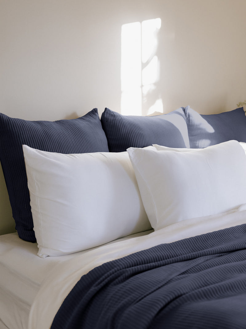 Navy euro coverlet shams behind white pillows on bed