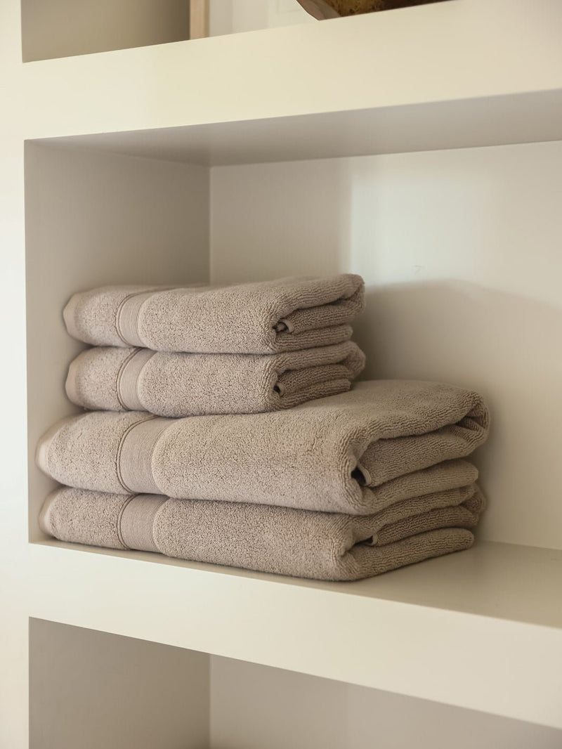 Sand hand towels and bath towels folded on shelf