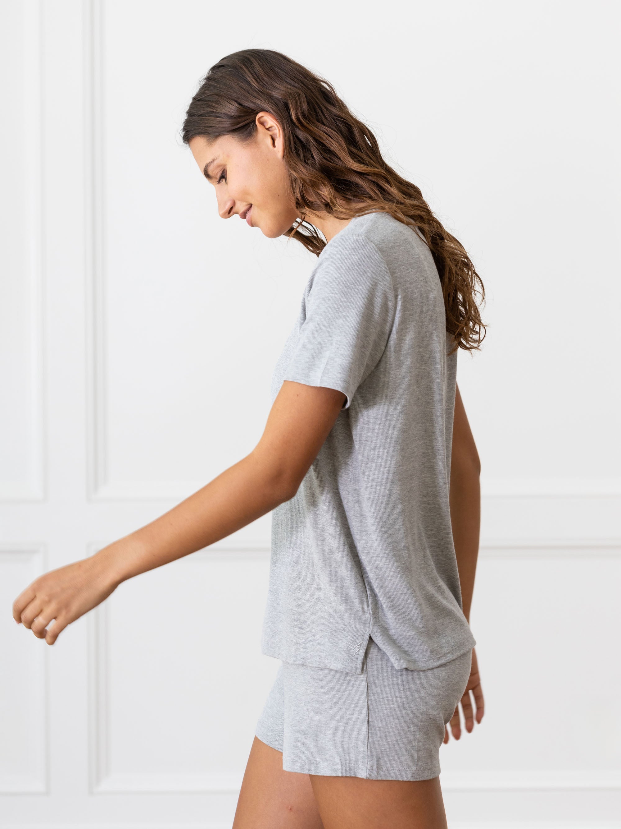 Woman wearing a grey Cozy Earth Rib Knit Short Sleeve Lounge Top and gray shorts against a white background 