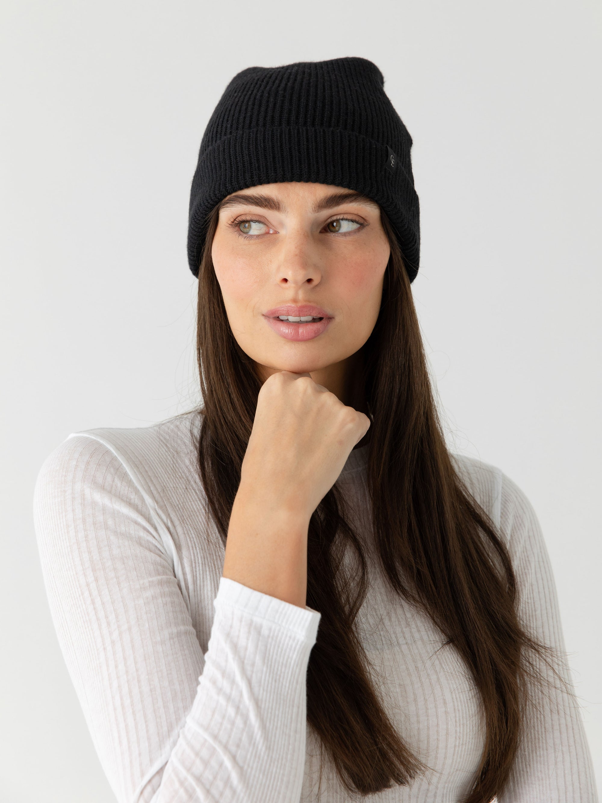Woman wearing a black knit beanie on a white background 
