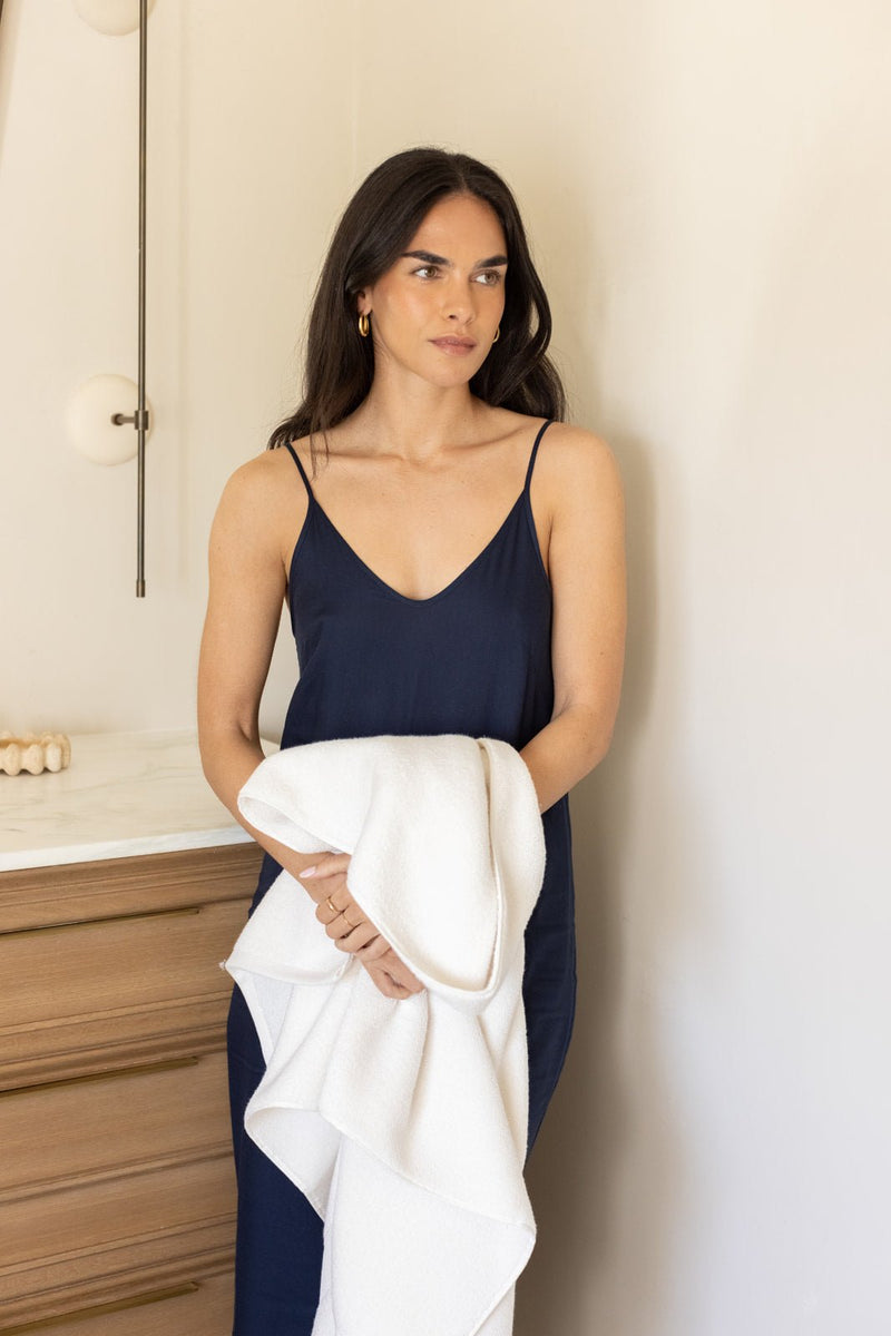 Woman in bathroom holding seashell luxe bath towel