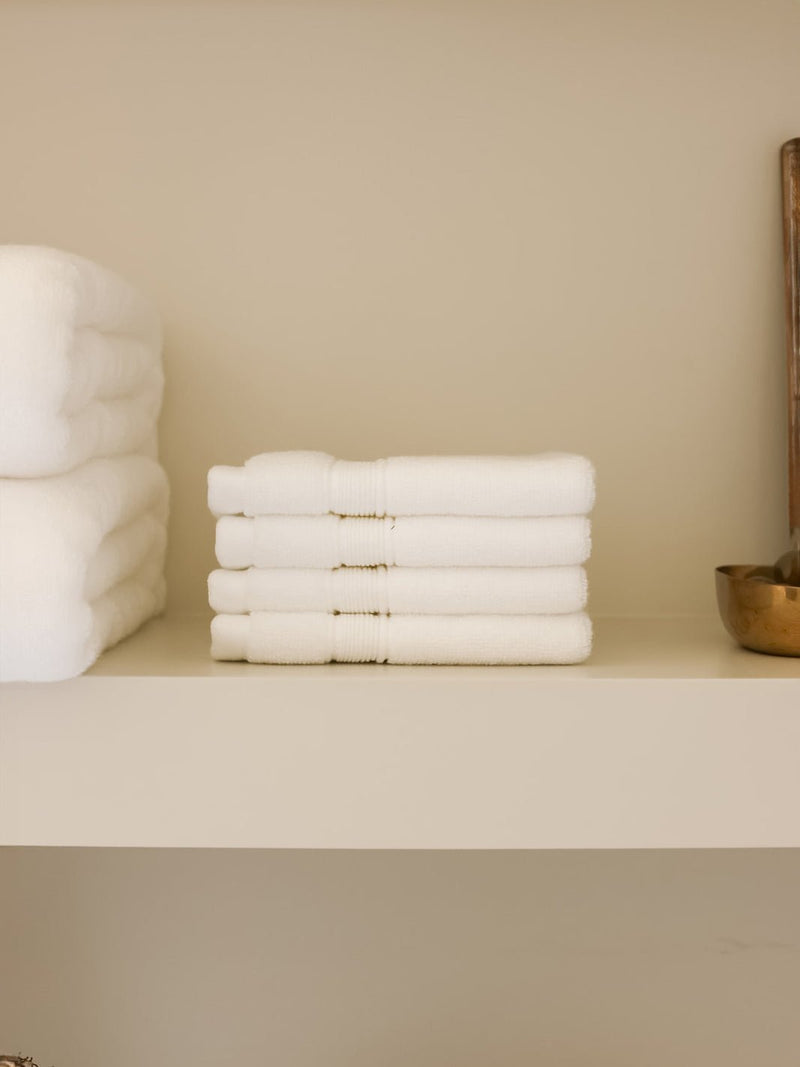 White luxe washcloths folded on shelf