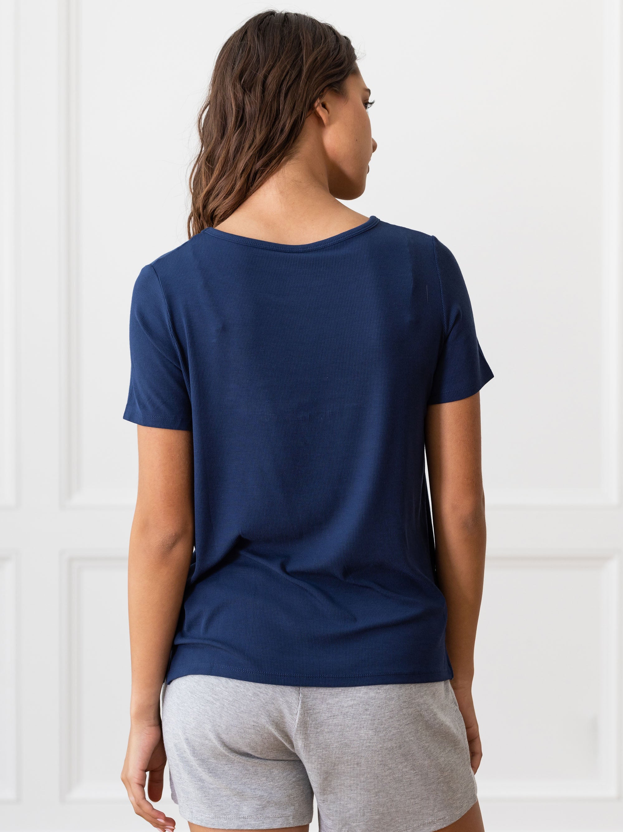 Woman wearing a blue Cozy Earth Rib Knit Short Sleeve Lounge Top and gray shorts against a white background 