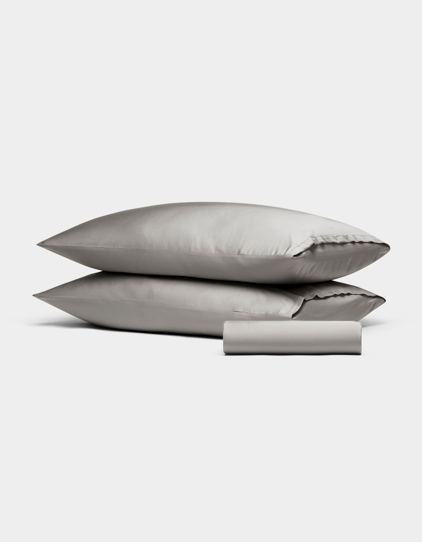 The Cozy Earth Bamboo Bedding Basic Bundle features two light gray pillowcases stacked together with a matching folded bedsheet in front, all displayed against a plain white background.|Color:Light Grey