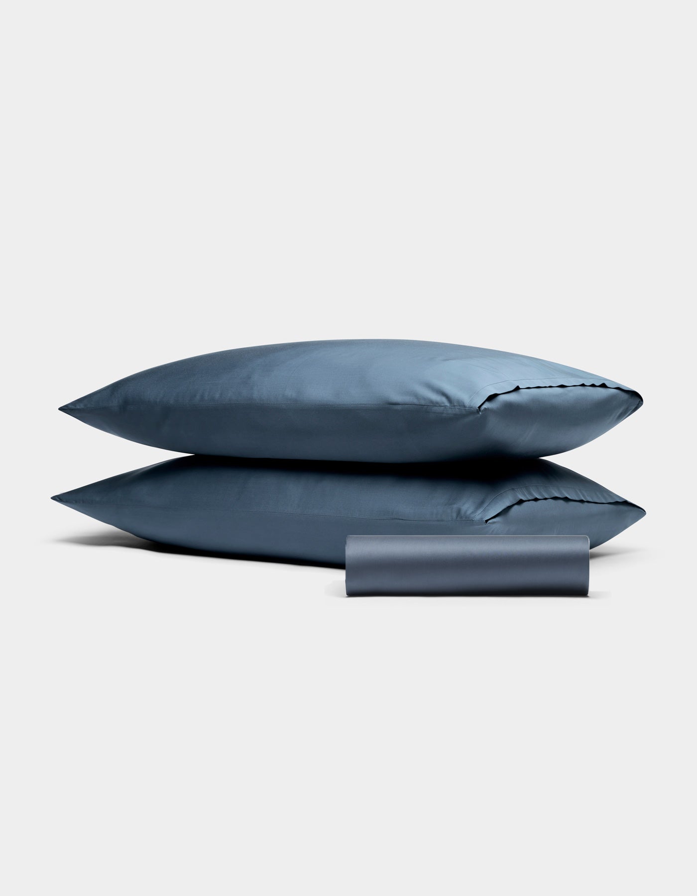 Cozy Earth Bamboo Bedding Basic Bundle: two stacked blue pillows with a matching rolled blue pillowcase on a plain light gray background.|Color:Pacific Blue