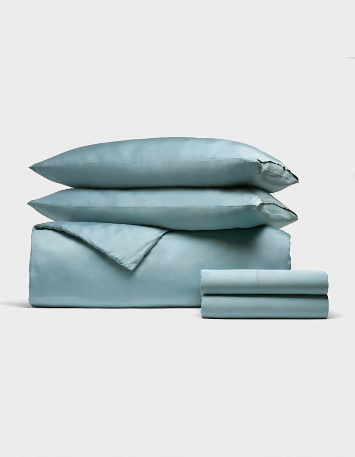 The Bamboo Bedding Deluxe Bundle by Cozy Earth features a neatly folded light blue set—including two pillows, a duvet cover, and sheets—elegantly displayed against a plain white background. |Color:River