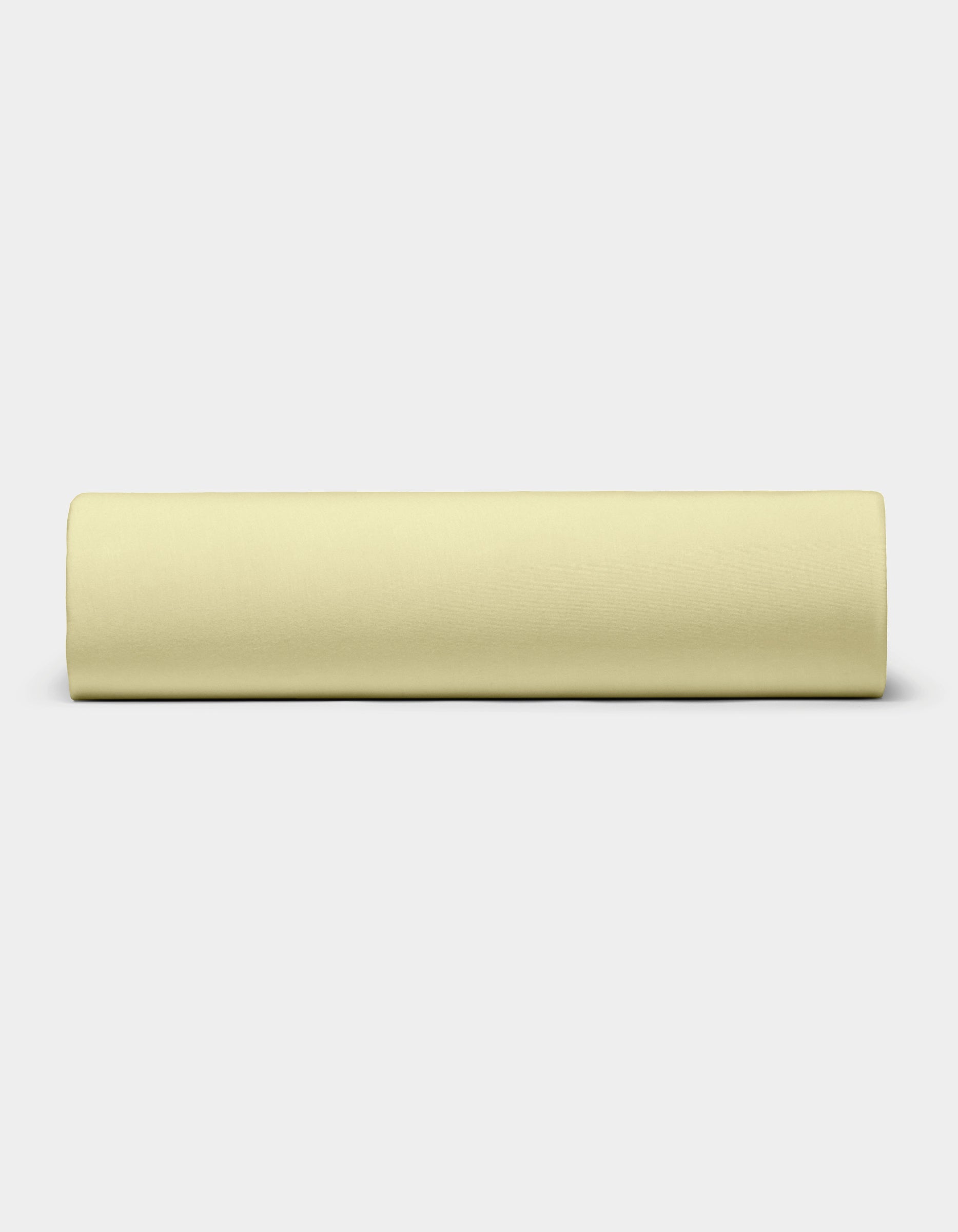 The Bamboo Jersey Sheet Set by Cozy Earth, in pale yellow, is neatly rolled and placed horizontally on a plain white background.