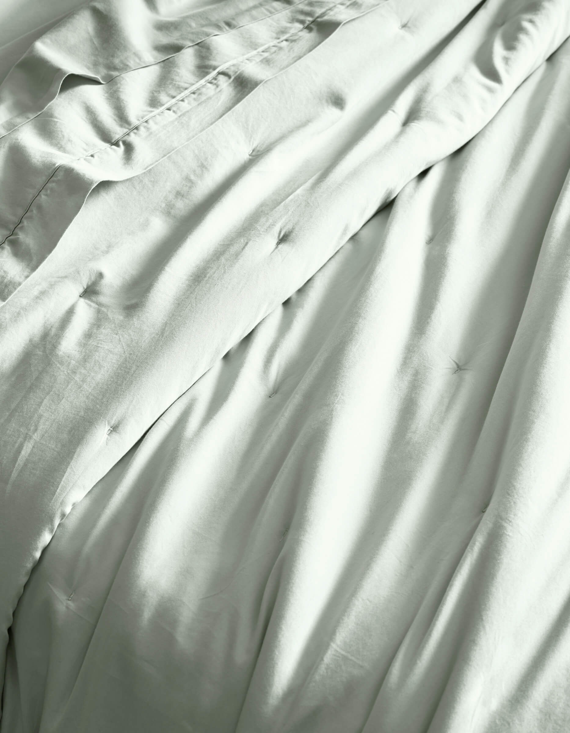 Close-up of Cozy Earth’s Soft-Wash Cotton Quilt, showcasing its light color, gentle folds, and subtle tufted details for a soft, comfortable, and inviting bed.