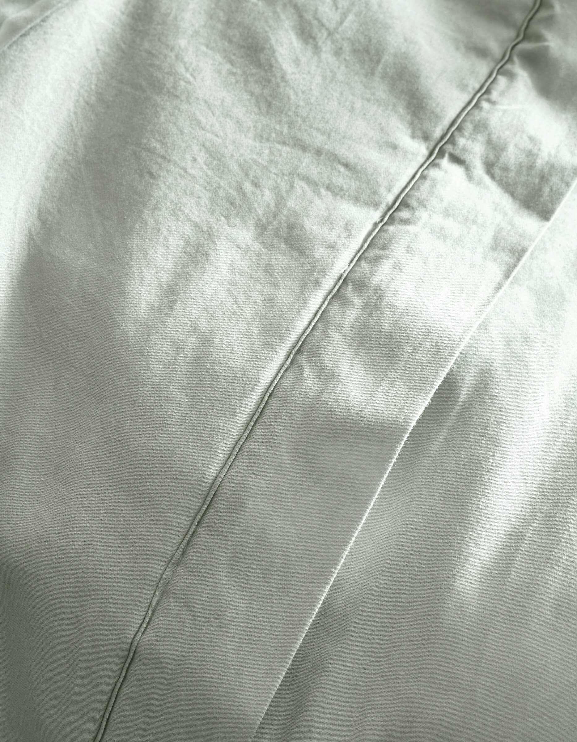 Close-up of Cozy Earth's Soft-Wash Cotton Quilt in light gray, highlighting the diagonal seam, soft folds, and textured fabric.