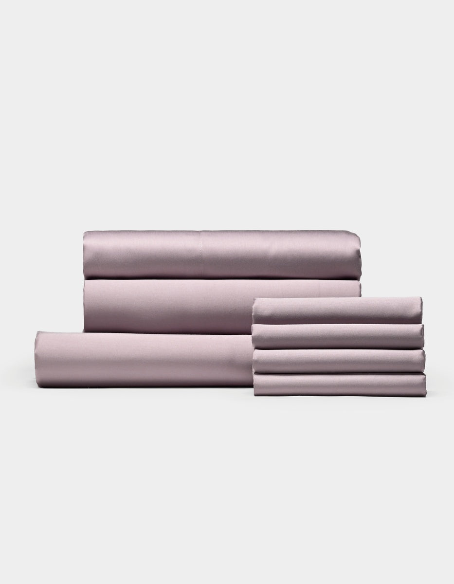 A neatly folded set of Cozy Earth Bamboo Bedding Core Bundle sheets and pillowcases, including both flat and fitted sheets, arranged against a plain white background.
